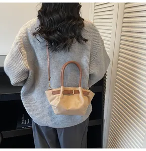 Detail of suede bucket bag with decorative brown leather belt and round handle