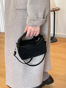 Große schwarze minimalistische Tragetasche mit Griff und goldenen Details am Modell