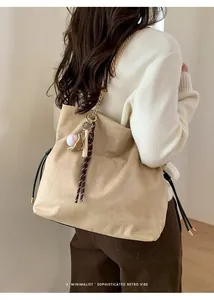 Dettaglio borsa tote in pelle scamosciata beige con catena oro e ciondoli baseball