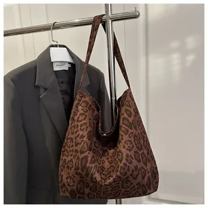 Détail d'un sac cabas à imprimé léopard suspendu avec un blazer gris pour un look chic