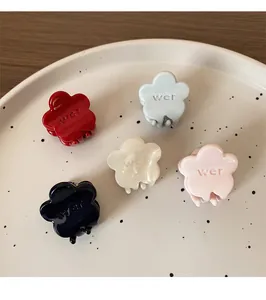 Set of five colorful flower hair claws in cream, blue, pink, red, and black on a tray