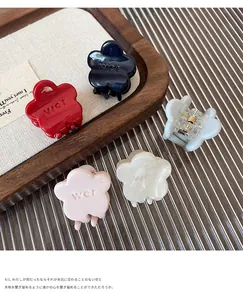 Detailed close-up of small floral hair claws in cream colors on a wooden tray