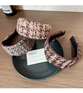 Trois serre-têtes larges en maille de tweed pastel disposés sur un plateau déco