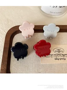 Set of small flower hair claws in pink, blue, black, and red on a wooden display tray