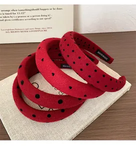 Detail of red polka dot plush headbands stacked on books showing handmade texture