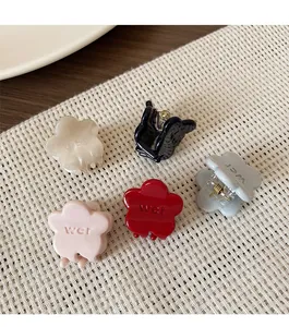 Detailed macro view of mini flower hair claws in five colors with embossed texture