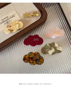 Détail de barrettes nuages en acétate avec clips métalliques et gravures fait main