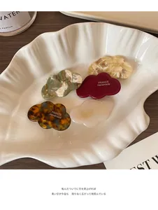 Détail de cinq pinces à cheveux en acétate en forme de nuage aux couleurs variées sur un plateau