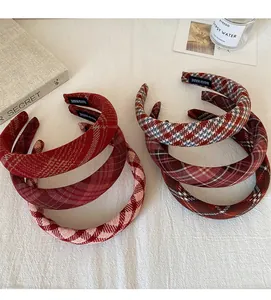 Close-up of handmade red plaid padded headbands with black woven label on white fabric