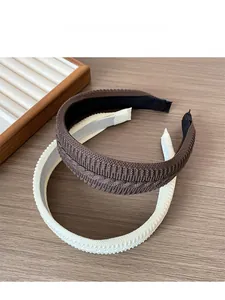 Detail of two knitted headbands in brown and beige colors on a warm wooden surface