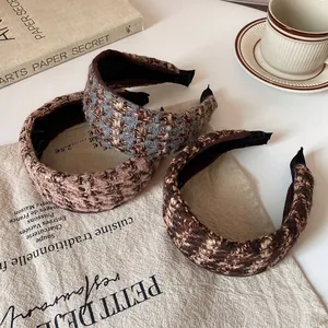 Trois serre-têtes larges en tricot rayé rose, bleu et marron présentés sur une table