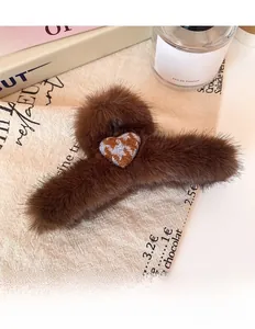Detailed view of dark brown plush heart hair claw clip on elegant fabric background