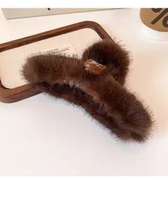 Detail view of brown plush hair claw clip with a blue houndstooth heart patch on a tray
