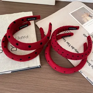 Red and black polka dot plush headbands set on a vintage wooden table with books
