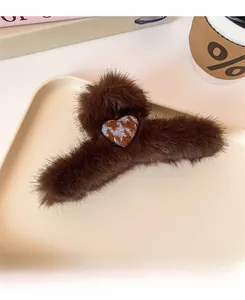 Detail of dark brown plush claw clip with heart checkerboard charm on a stylish tray