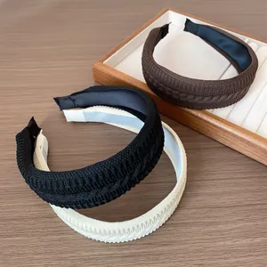 Braided knit wide headband set in black, coffee, and beige colors on a wooden surface