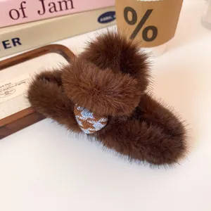 Brown plush heart hair claw clip with checkered pattern on a minimalist desk setting