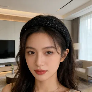 Serre-tête épais en tricot noir à paillettes porté par un mannequin dans un salon douillet