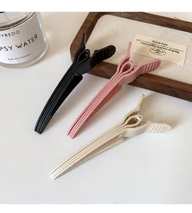 Three-piece set of matte styling hair clips in black, dusty rose, and off-white colors