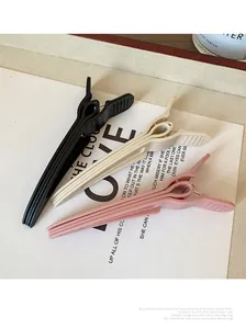 Close-up of matte hair clips in black, cream and pink with anti-slip texture