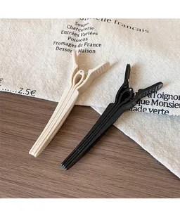 Detail shot of beige and black matte hair clips on a textured rustic fabric surface