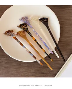 Close-up of elegant acetate hair pins featuring a fan-shaped design with a white pearl accent
