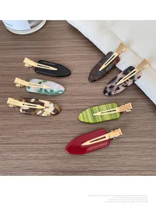 Detail view of colorful acetate hair clips with marble patterns and gold metal base