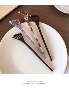 Detailed macro view of four acetate hair sticks with shell patterns and pearl accents