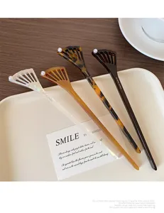Detail view of acetate hair sticks with fan-shaped heads and elegant pearl accents