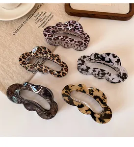 Detail of five leopard print cloud hair claws in various patterns on a rustic linen background