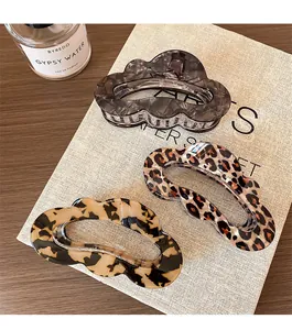 Three elegant leopard and tortoiseshell cloud hair claws on a rustic linen background