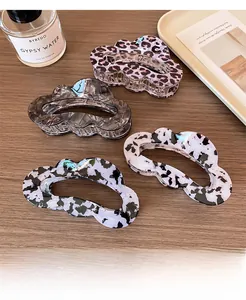 Close-up of leopard print and marble pattern claw clips on a wooden tabletop