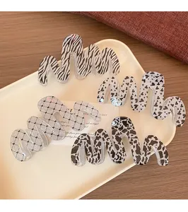 Detail showing four wavy glitter claw clips in marble and heart patterns on ceramic tray