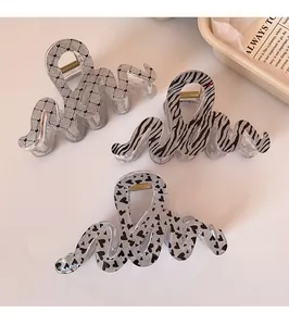 Detailed view of leopard wave hair claws with heart and zebra patterns on ivory background