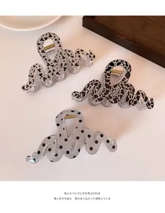 Close-up of set of three wavy snake-shaped acrylic hair clips with leopard and heart patterns