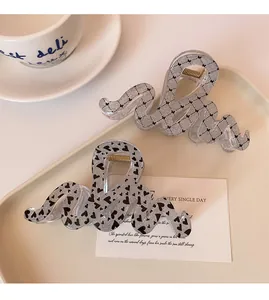 Detail of wave-shaped hair claws with black hearts and butterfly patterns on cream tray