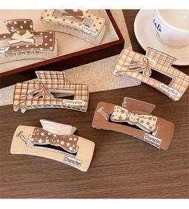 Detail of assorted brown plaid bow hair claws on a wooden table with a coffee cup