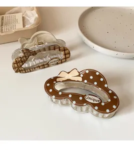 Detail of cream and brown hair claws with unique patterns and cute bow designs