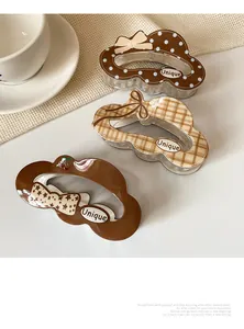 Close-up of three cute unique bow hair claws with polka dots, plaid, and cherry patterns