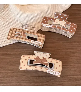 Macro shot of brown plaid and polka dot hair claws with cute bow details on wooden background