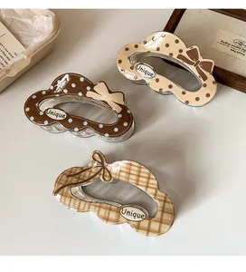 Detail showing three large cloud-shaped hair claws with polka dots and Unique logo