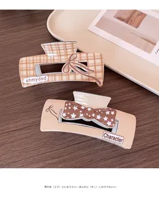 Detail of Korean style brown checkered hair claw clip and star bow design on wood