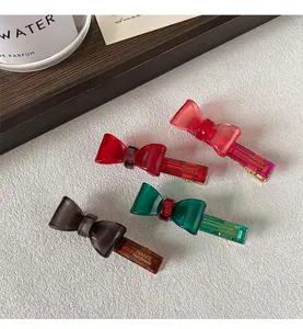 Detail of four resin bow hair clips in assorted colors with gold metal duckbill clips