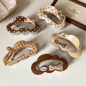 Set of five vintage brown hair claws with dots, plaid, and bows on a cream background