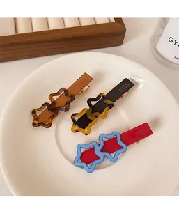 Gros plan sur trois barrettes à cheveux en acrylique avec étoiles colorées et logo