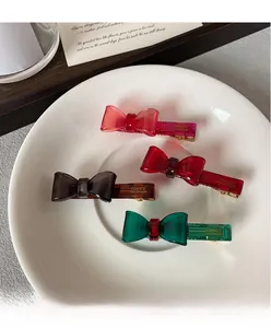 Detail of four colorful acrylic bow hair clips with France Handmade text on gold metal