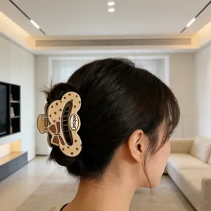 Beige polka dot hair claw clip with bow and 'Unique' lettering shown on a model