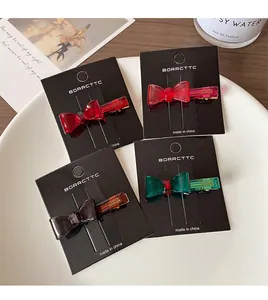 Detailed view of four colorful acrylic bow hair clips on a premium brand display card