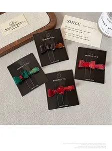 Close-up of four colorful resin bow hair clips in red and green on display cards