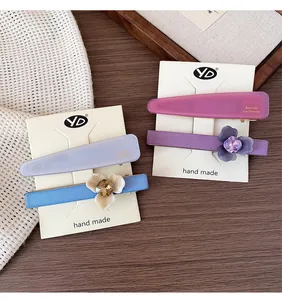 Détail de barrettes à fleurs en acétate avec strass sur carte de présentation blanche